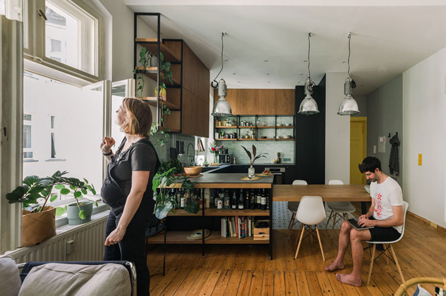 Couple in a modern kitchen with green tile backsplash and open shelving.