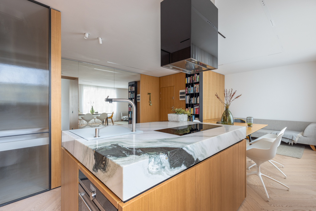 Contemporary kitchen with a marble countertop island and wood accents in a Berlin apartment.