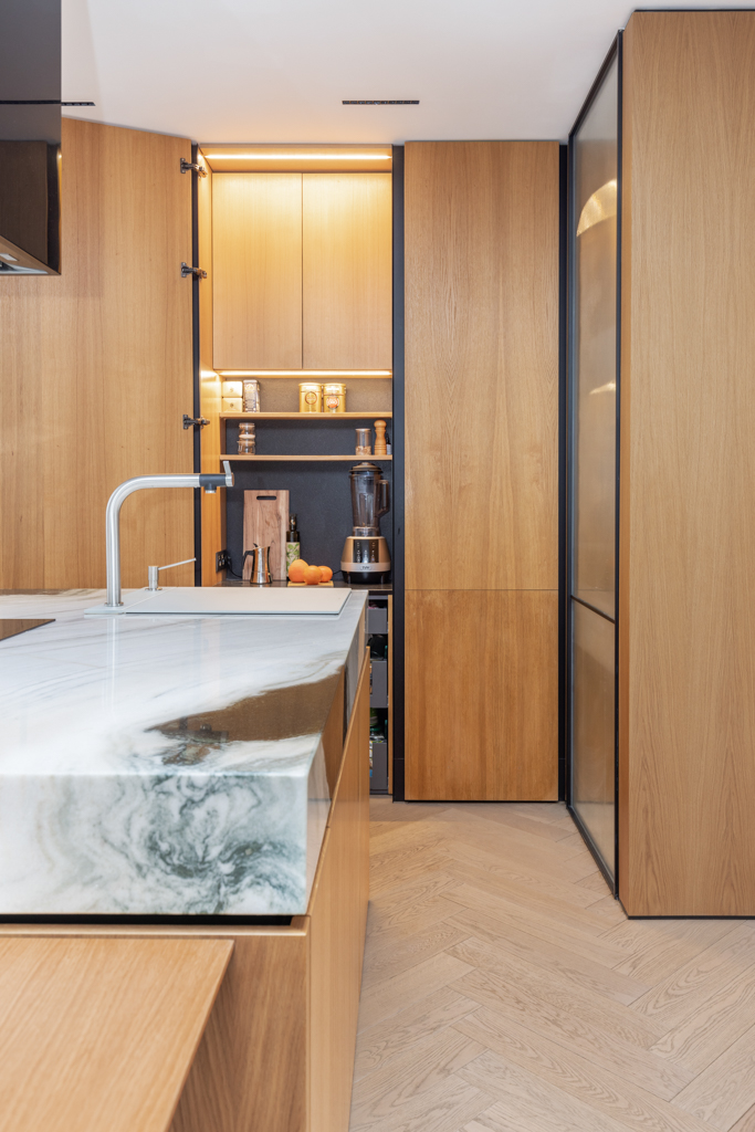 Sleek modern kitchen with wood cabinetry and marble countertop in a Berlin apartment.