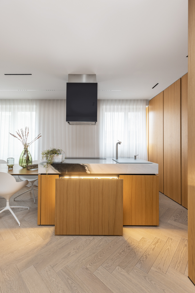 Modern kitchen island with wood finish and marble countertop in a minimalist Berlin apartment.