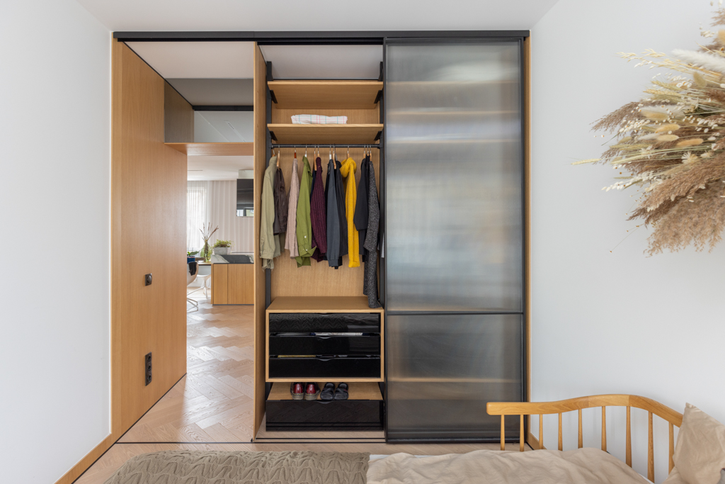 Modern design bedroom with wooden bed frame and sliding wardrobe doors.