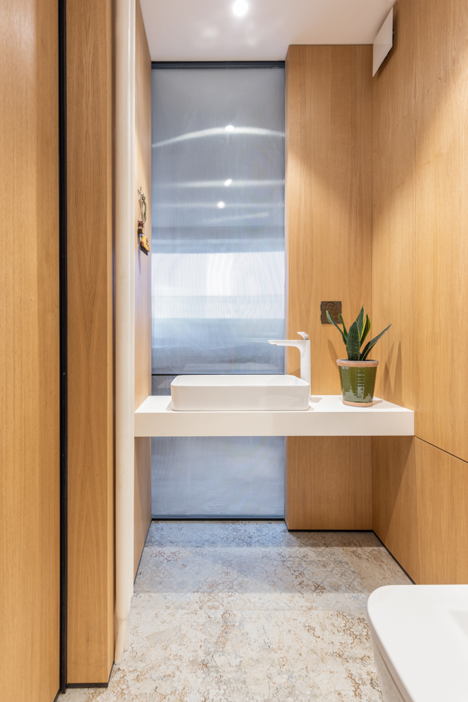 Modern bathroom with light wood paneling and a minimalist floating sink.